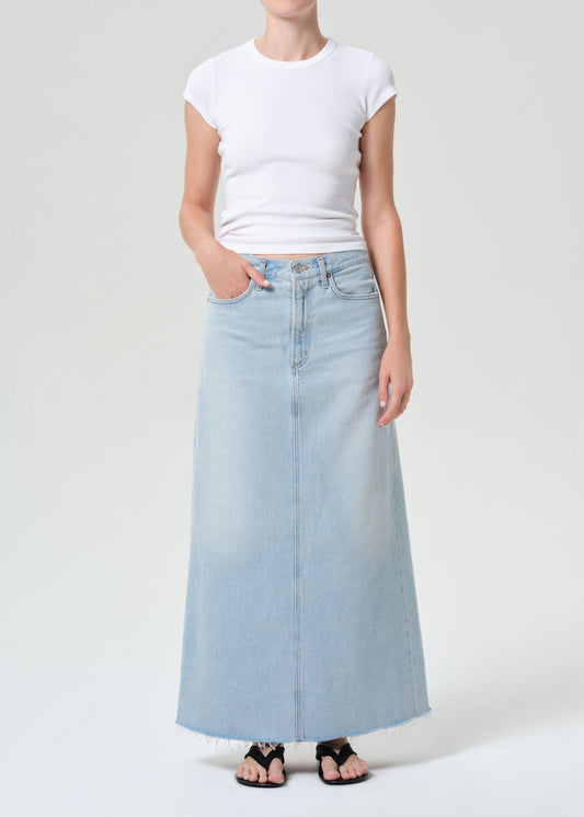 Person wearing a white t-shirt and light blue denim skirt on a white background