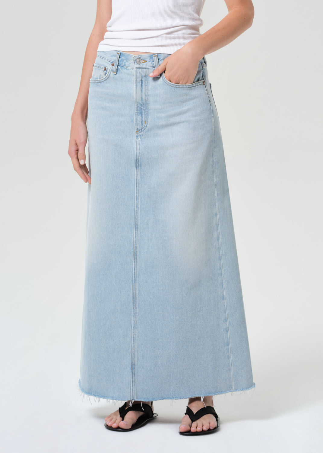 Person wearing a light blue denim skirt on a white background