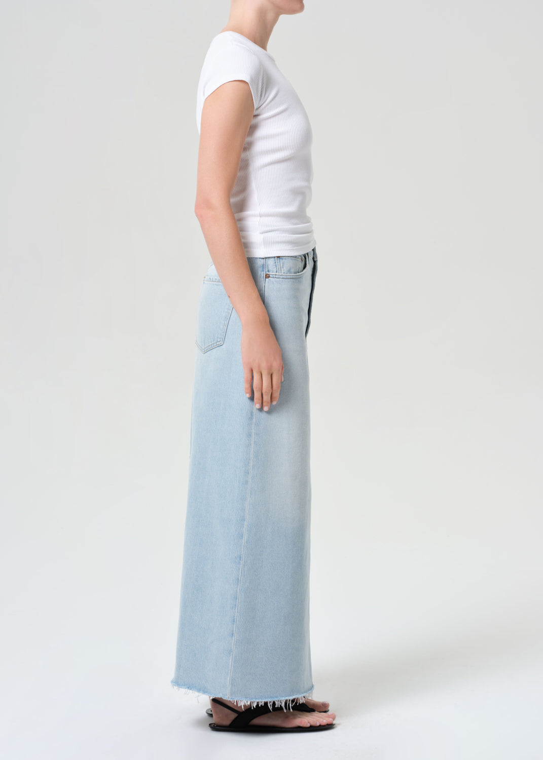 Person wearing a white t-shirt and light blue jeans on a plain background