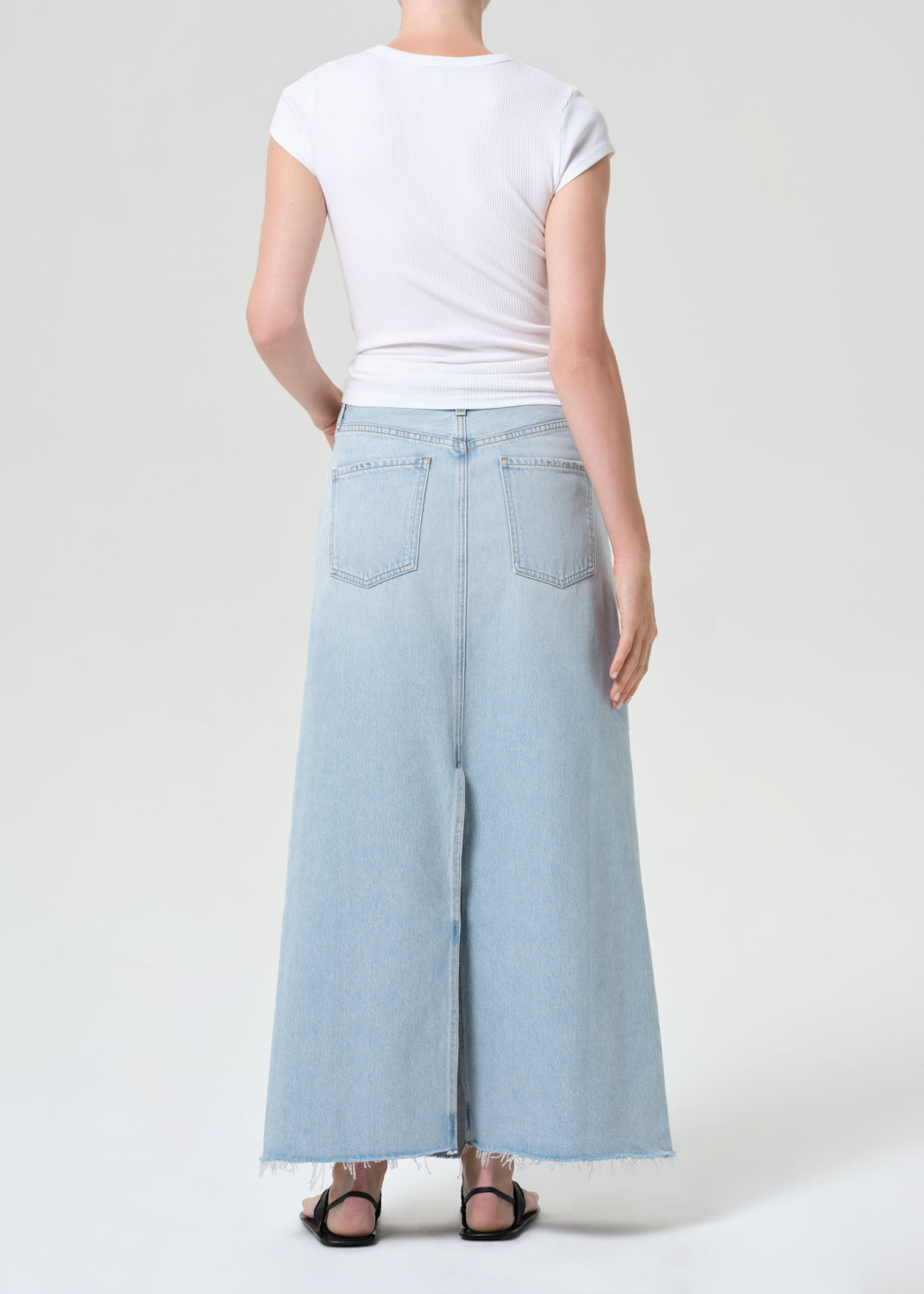 Person wearing light blue wide-leg jeans and a white t-shirt on a plain background