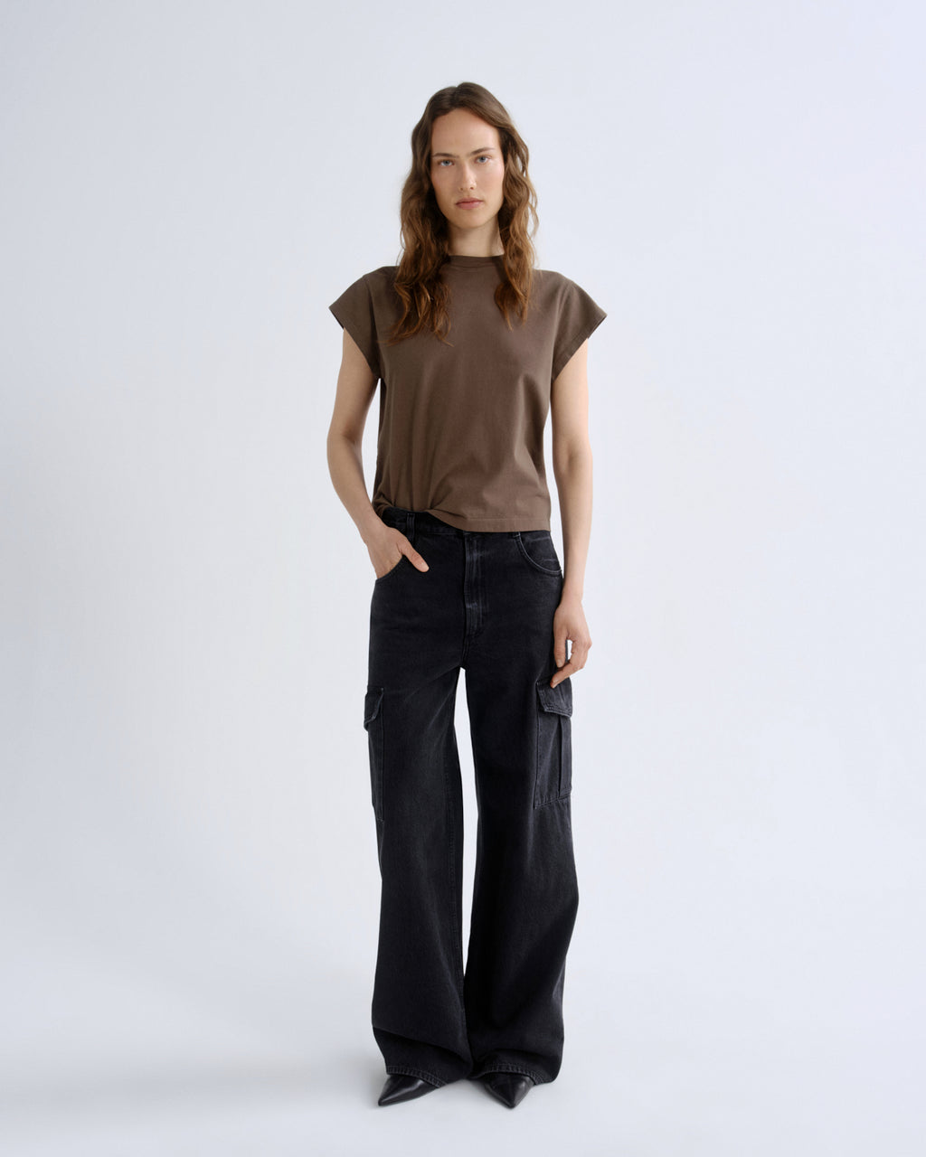 Woman wearing a brown top and black pants on a white background