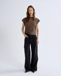 Woman wearing a brown top and black pants on a white background