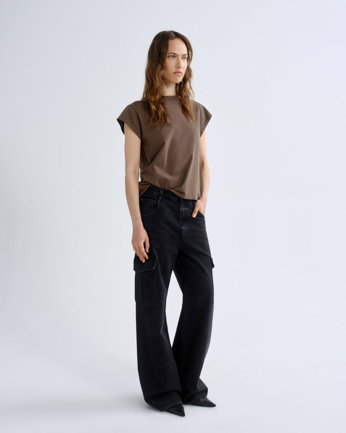 Person wearing a brown top and black pants on a white background