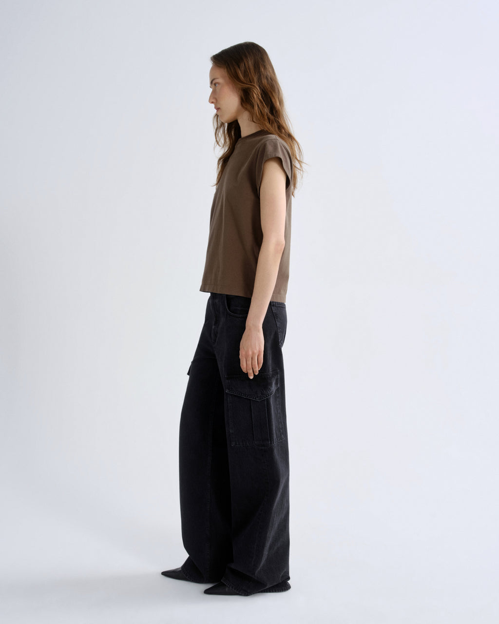 Woman wearing a brown sleeveless top and black cargo pants on a white background