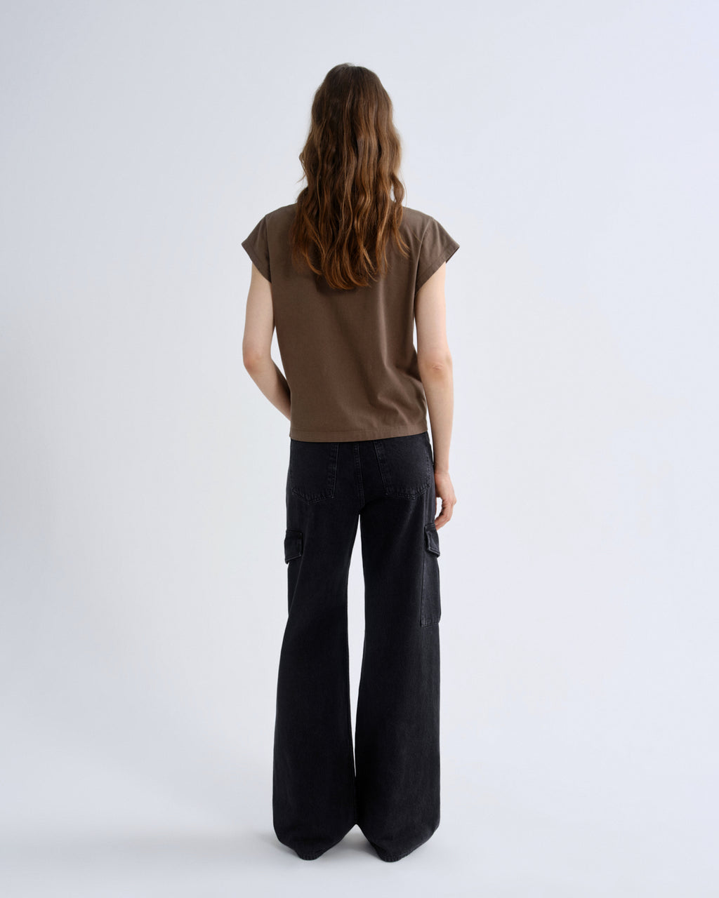 Person wearing a brown top and black pants on a white background