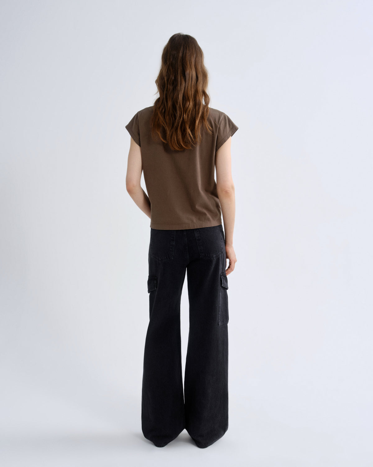 Person wearing a brown top and black pants on a white background