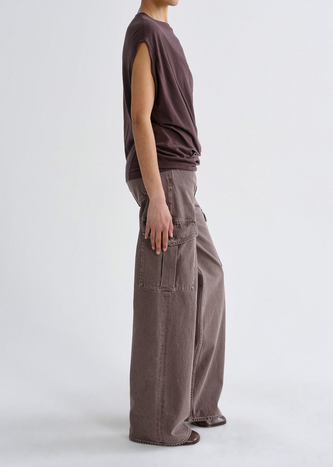 A model shown from the side wearing a dark brown sleeveless top and wide-leg taupe cargo pants against a grey background.