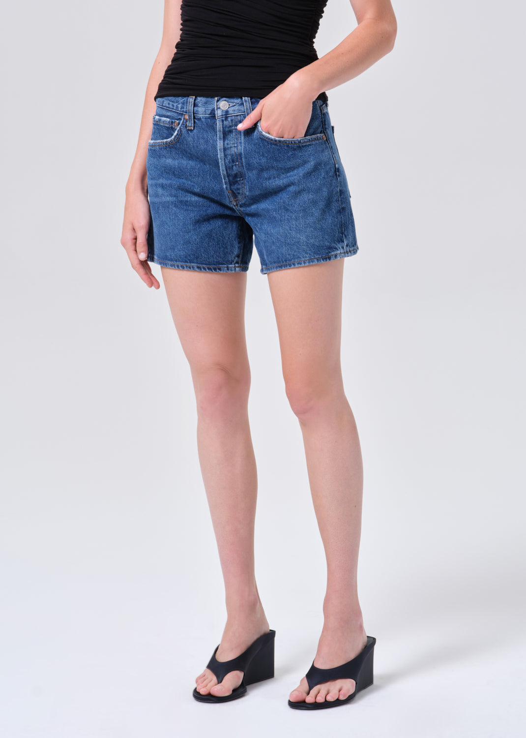 Person wearing blue denim shorts on a white background