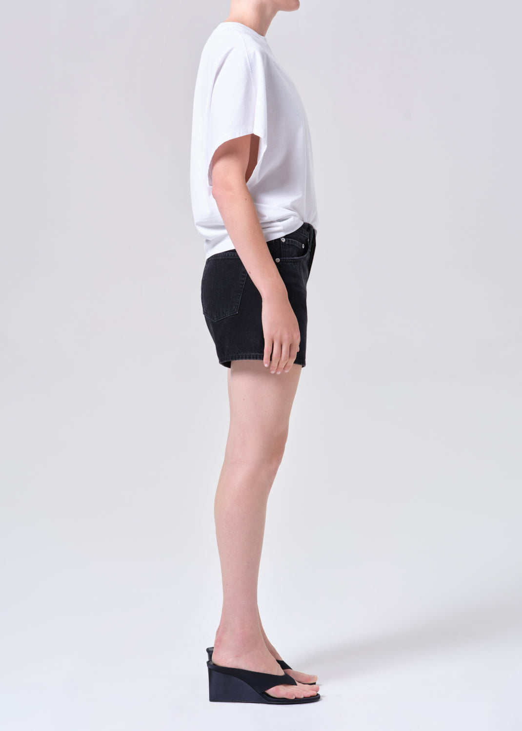 Person wearing a white t-shirt and black shorts on a plain background
