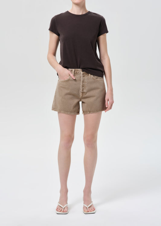 Person wearing a black t-shirt and beige shorts on a white background
