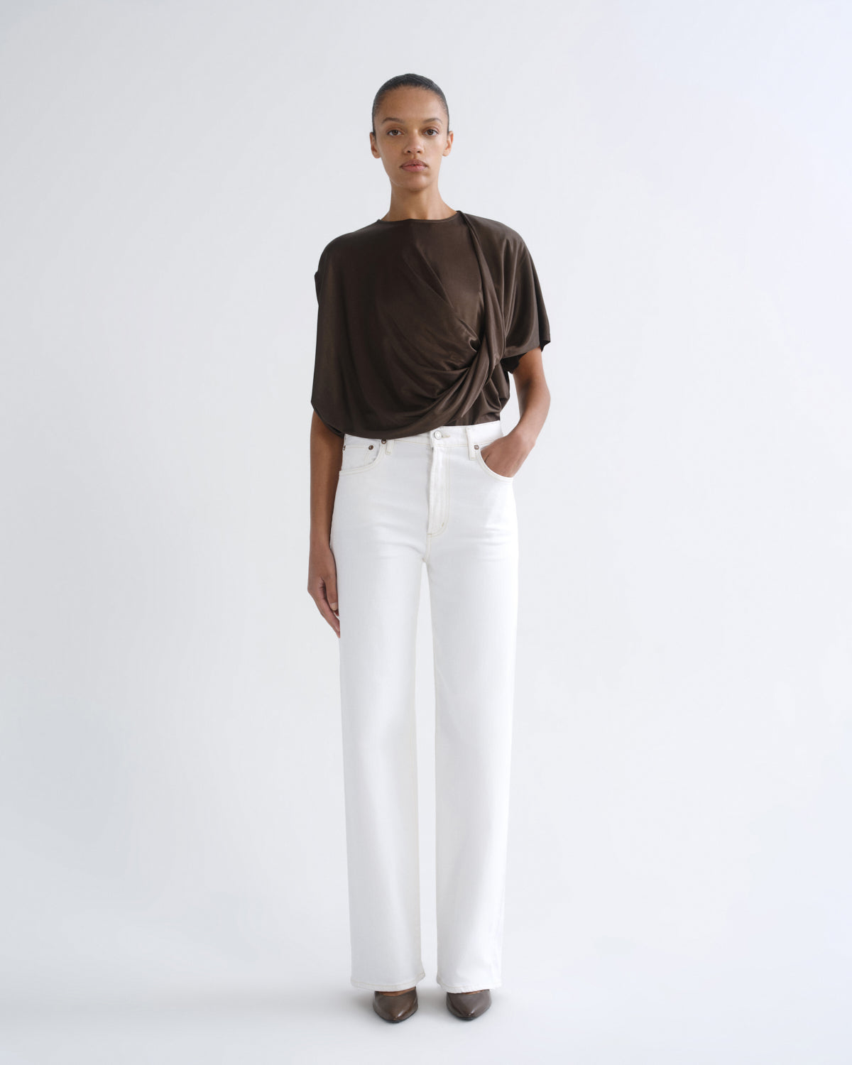 Person wearing brown short sleeve top and white jeans, front view