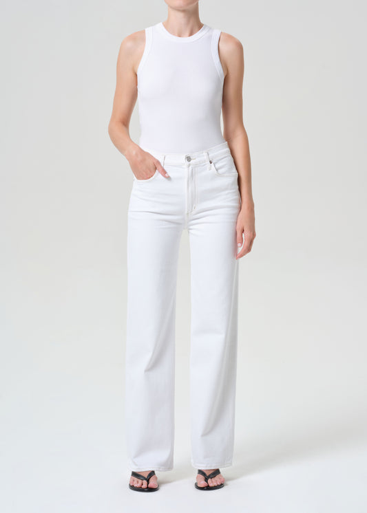 Person wearing a white sleeveless top and white pants on a plain background