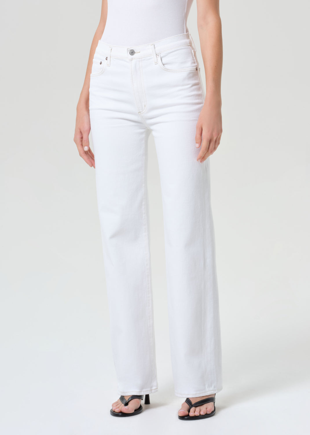 Person wearing white jeans on a plain background