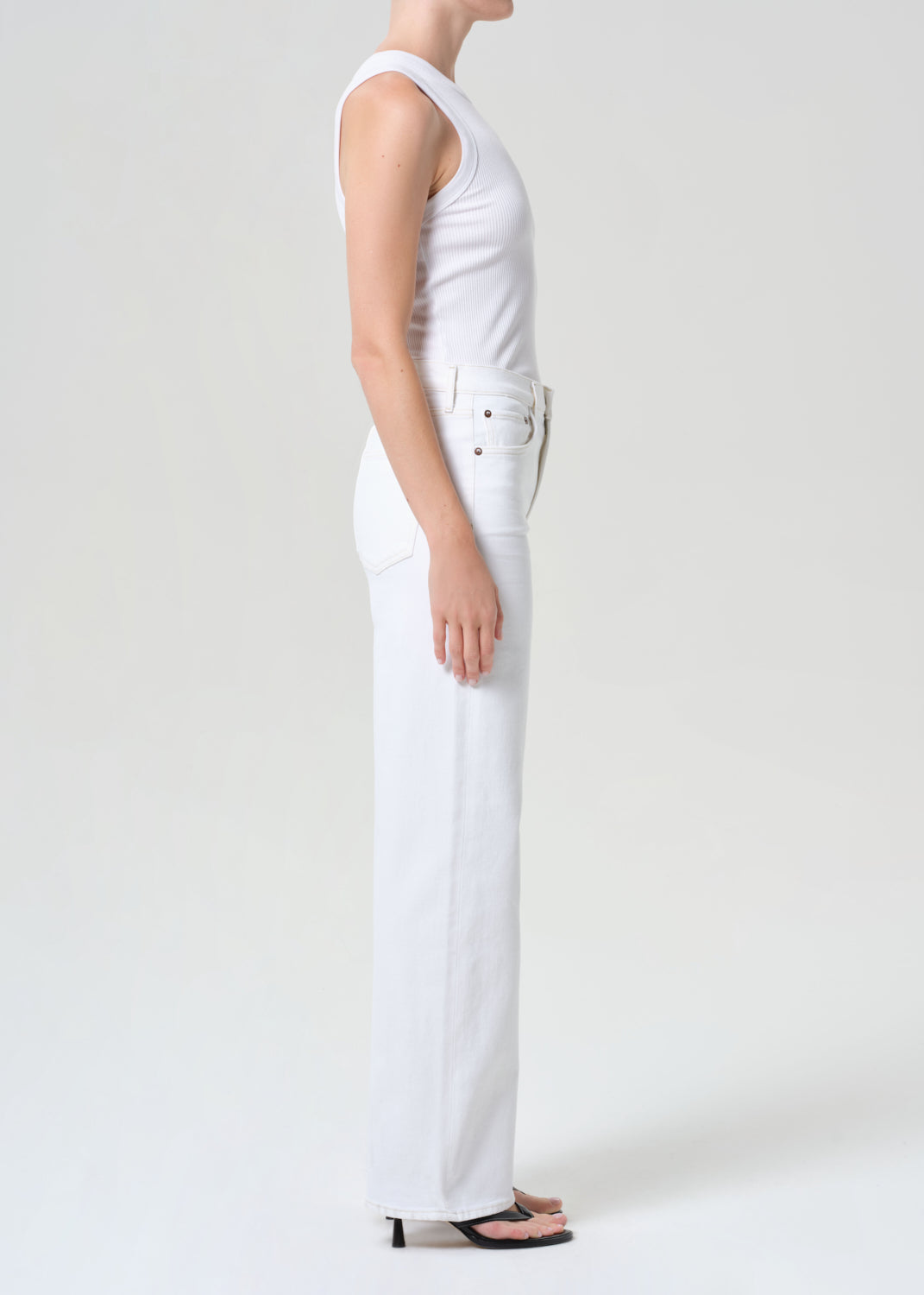 Person wearing a white sleeveless top and pants on a plain background