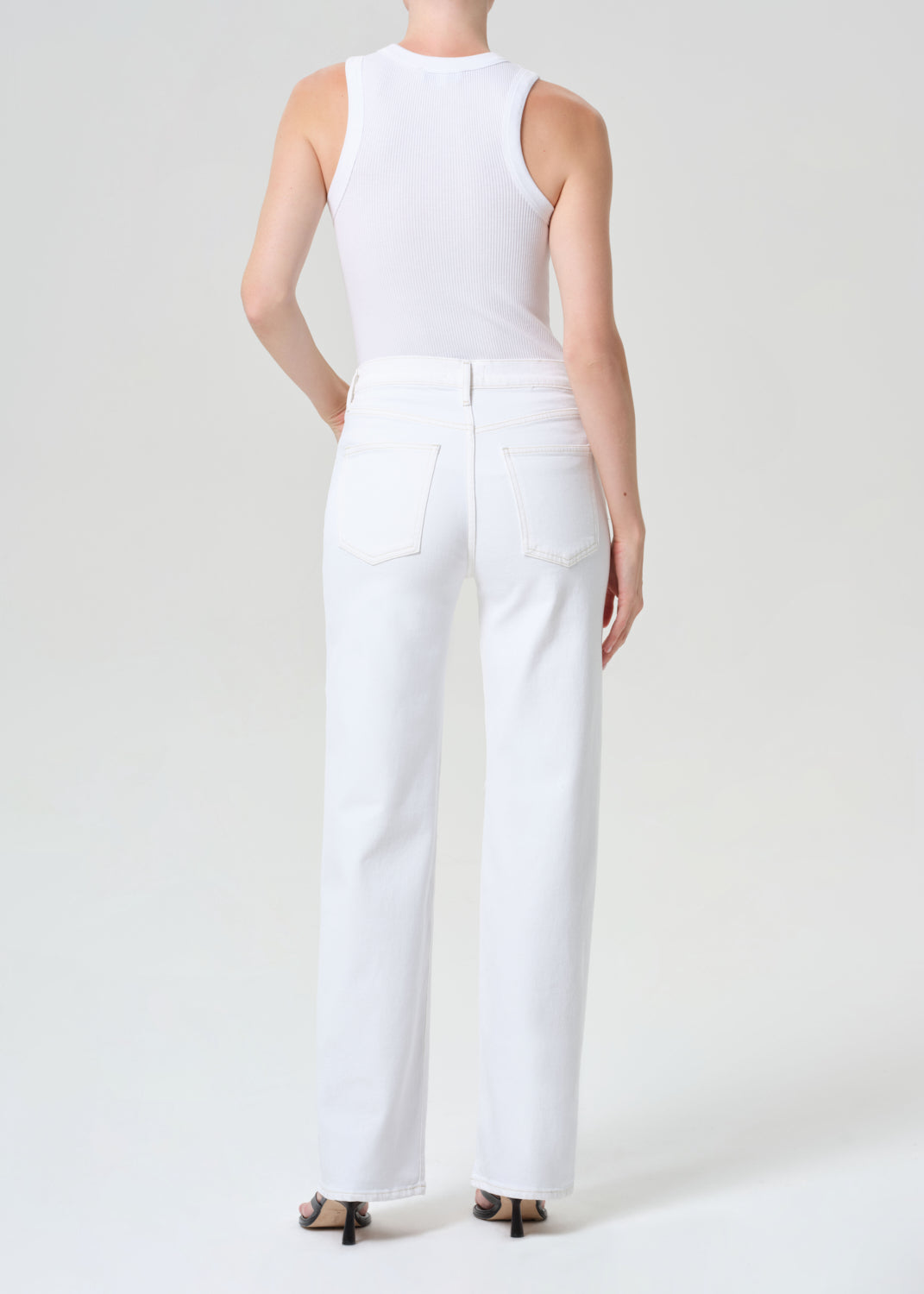 Person wearing a white sleeveless top and pants on a light gray background