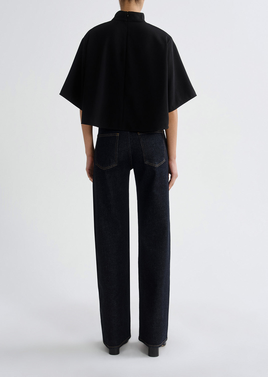Person wearing a black outfit with a grey background