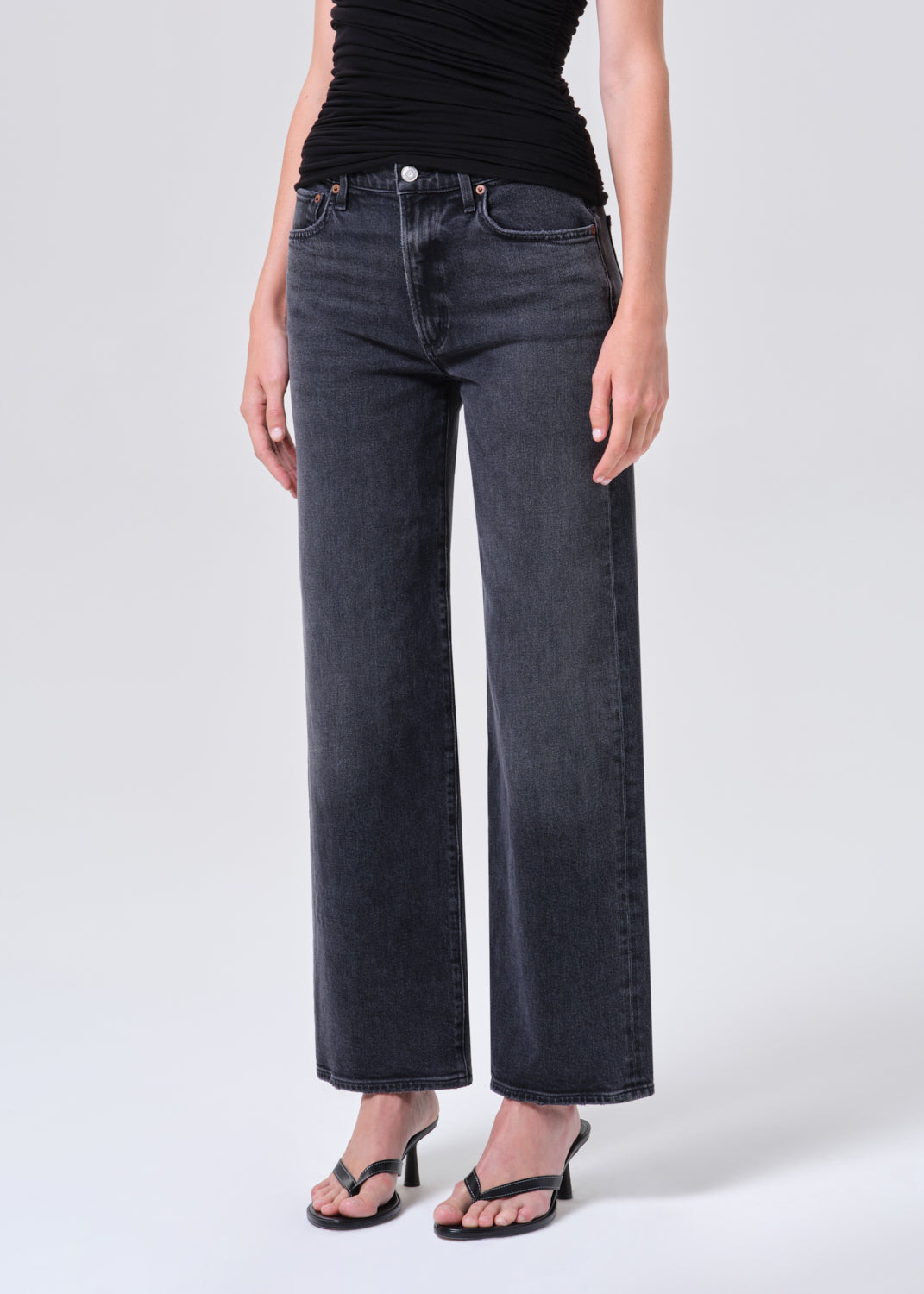 Person wearing black jeans and a black top on a white background