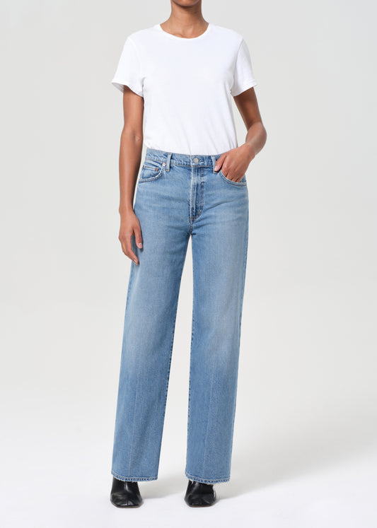 Person wearing light blue jeans and a white t-shirt on a white background