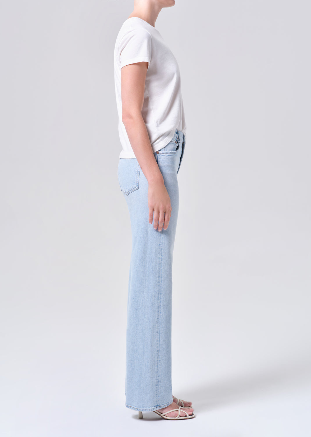 Person wearing light blue jeans and a white t-shirt on a plain background