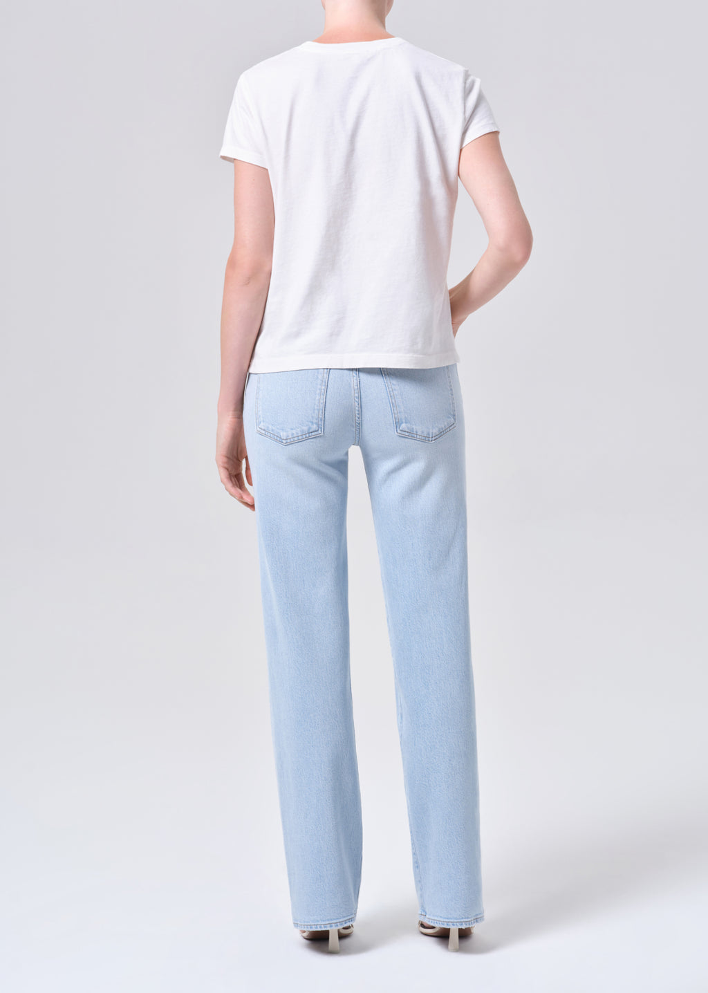Person wearing light blue jeans and a white t-shirt on a white background