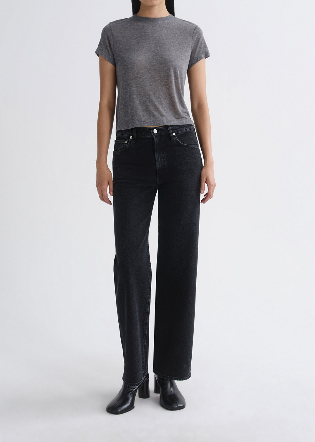 Person wearing a gray t-shirt and black jeans on a grey background