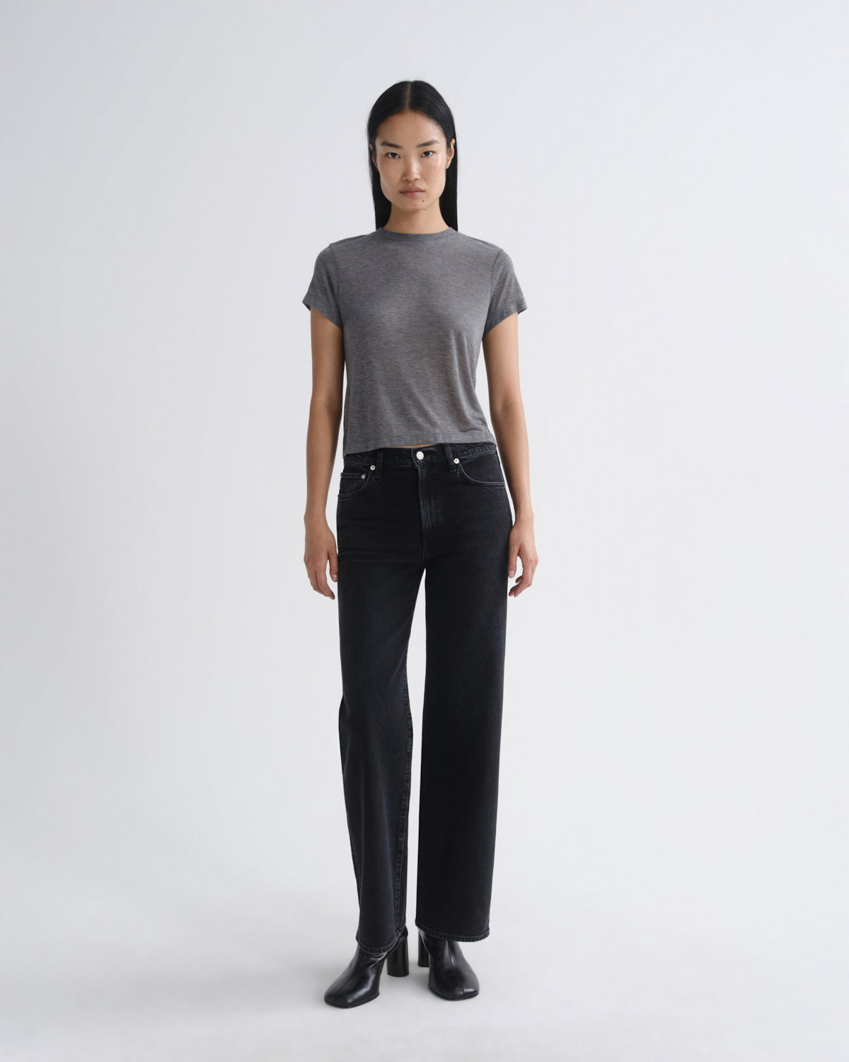 Person wearing a gray t-shirt and black jeans on a white background