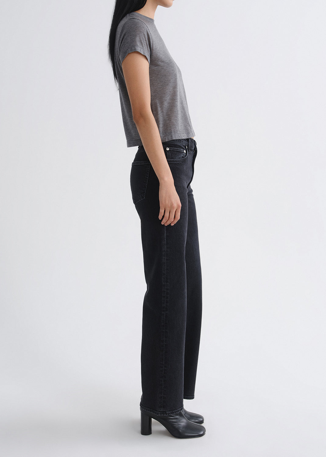 Person wearing black jeans and a gray shirt on a grey background