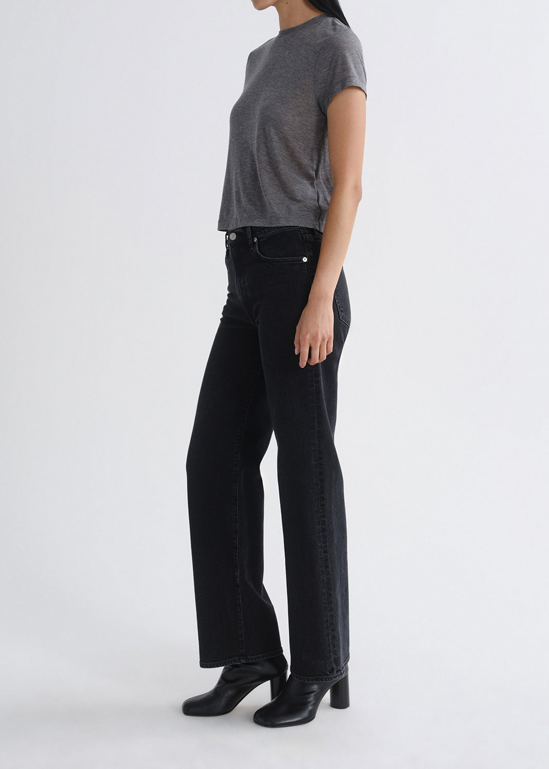 Person wearing black jeans and a gray top on a grey background