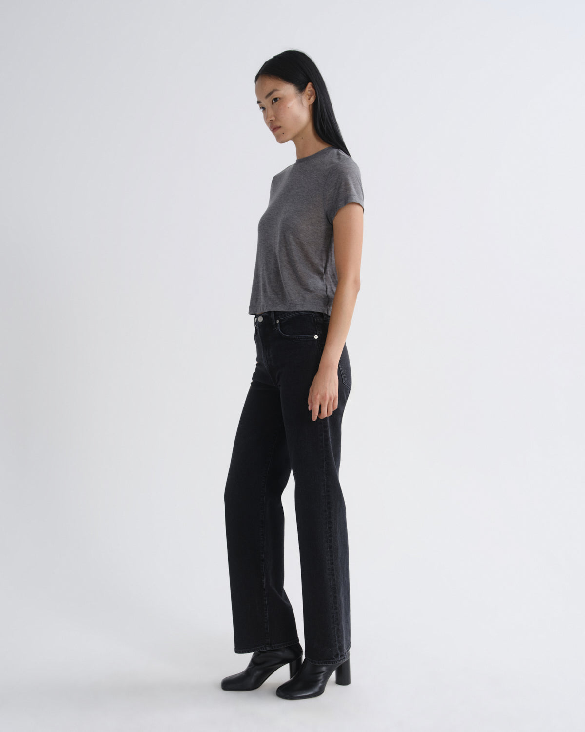 Woman wearing a gray t-shirt and black pants on a white background