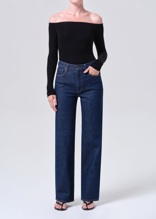 Person wearing a black off-shoulder top and blue jeans on a white background