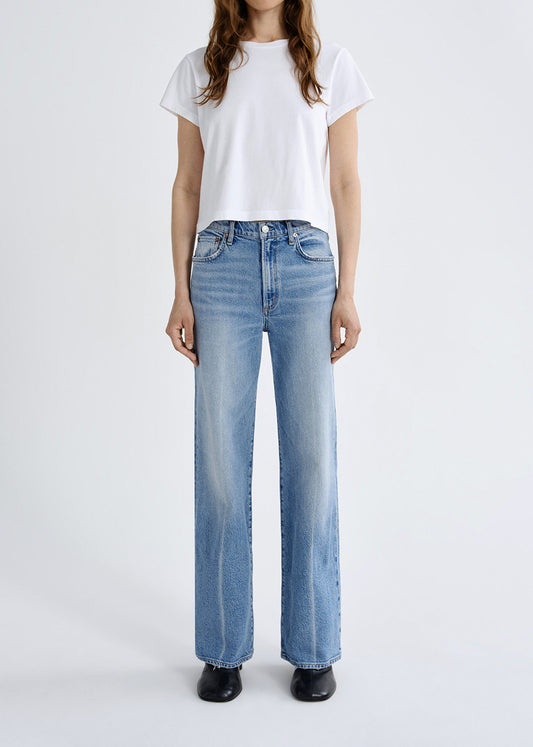 Person wearing light blue jeans and a white t-shirt on a white background