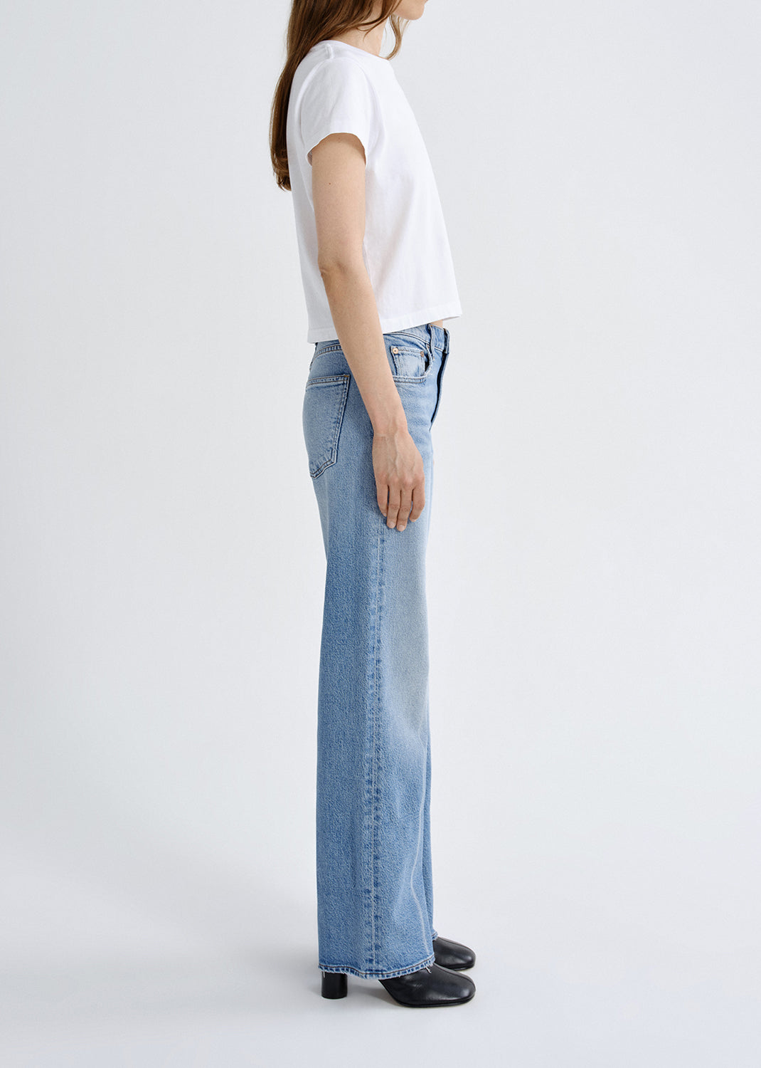 Person wearing a white t-shirt and light blue jeans on a white background