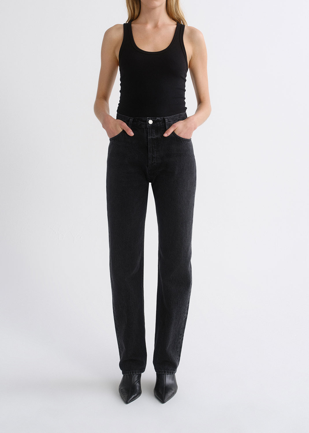 Person wearing black tank top and black pants on a grey background