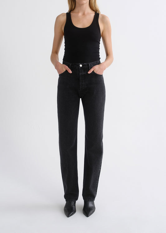 Person wearing black tank top and black pants on a grey background