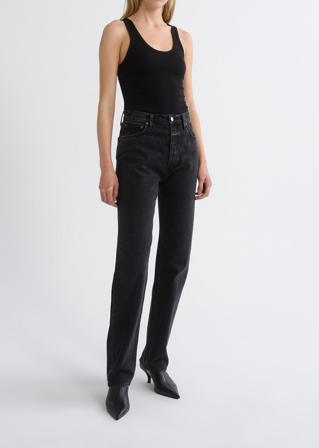 Person wearing black tank top and black pants on a grey background
