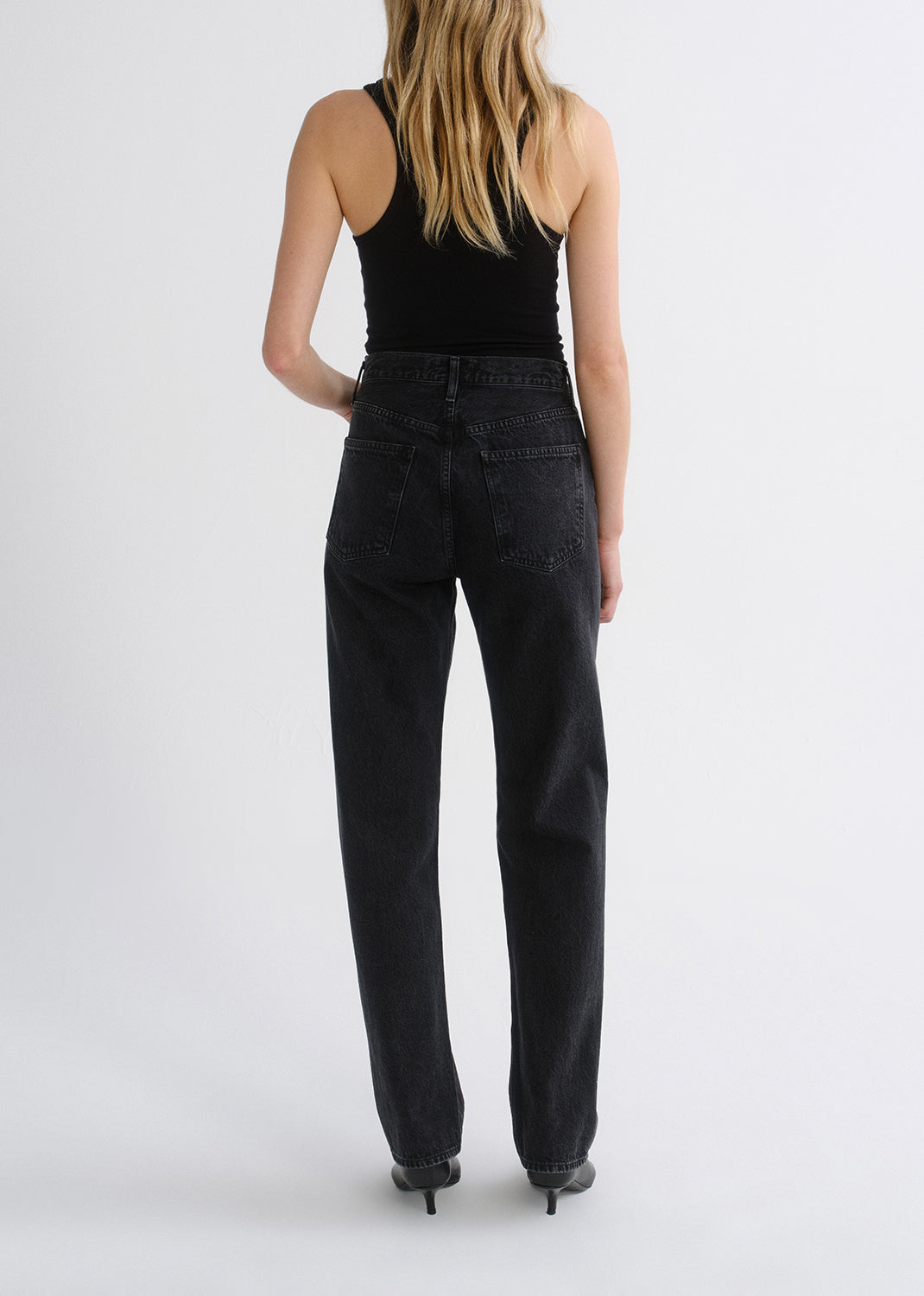 Person wearing black tank top and black pants on a grey background