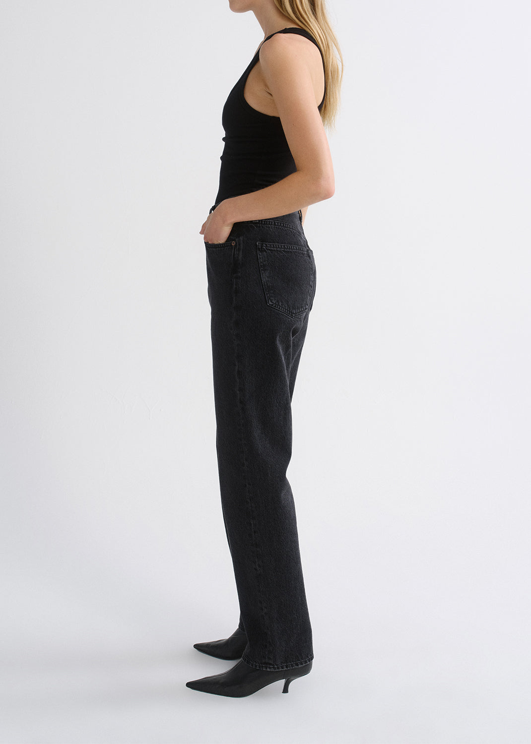Person wearing black tank top and black pants on a grey background