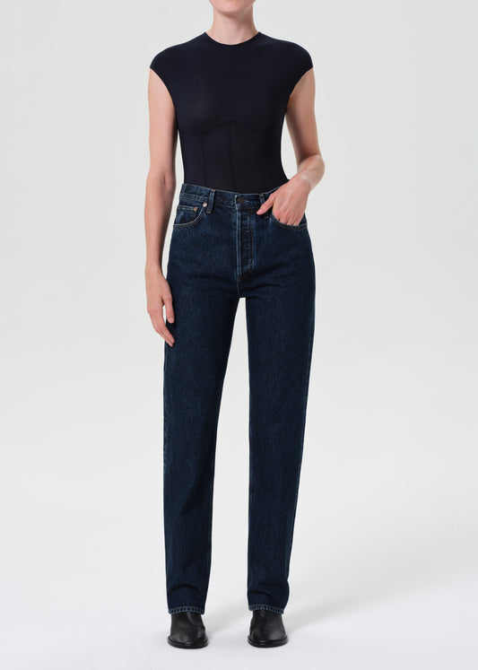 Person wearing dark blue jeans and a black sleeveless top on a white background