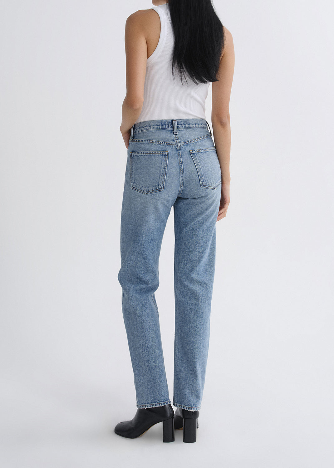 Person wearing light blue jeans on a grey background