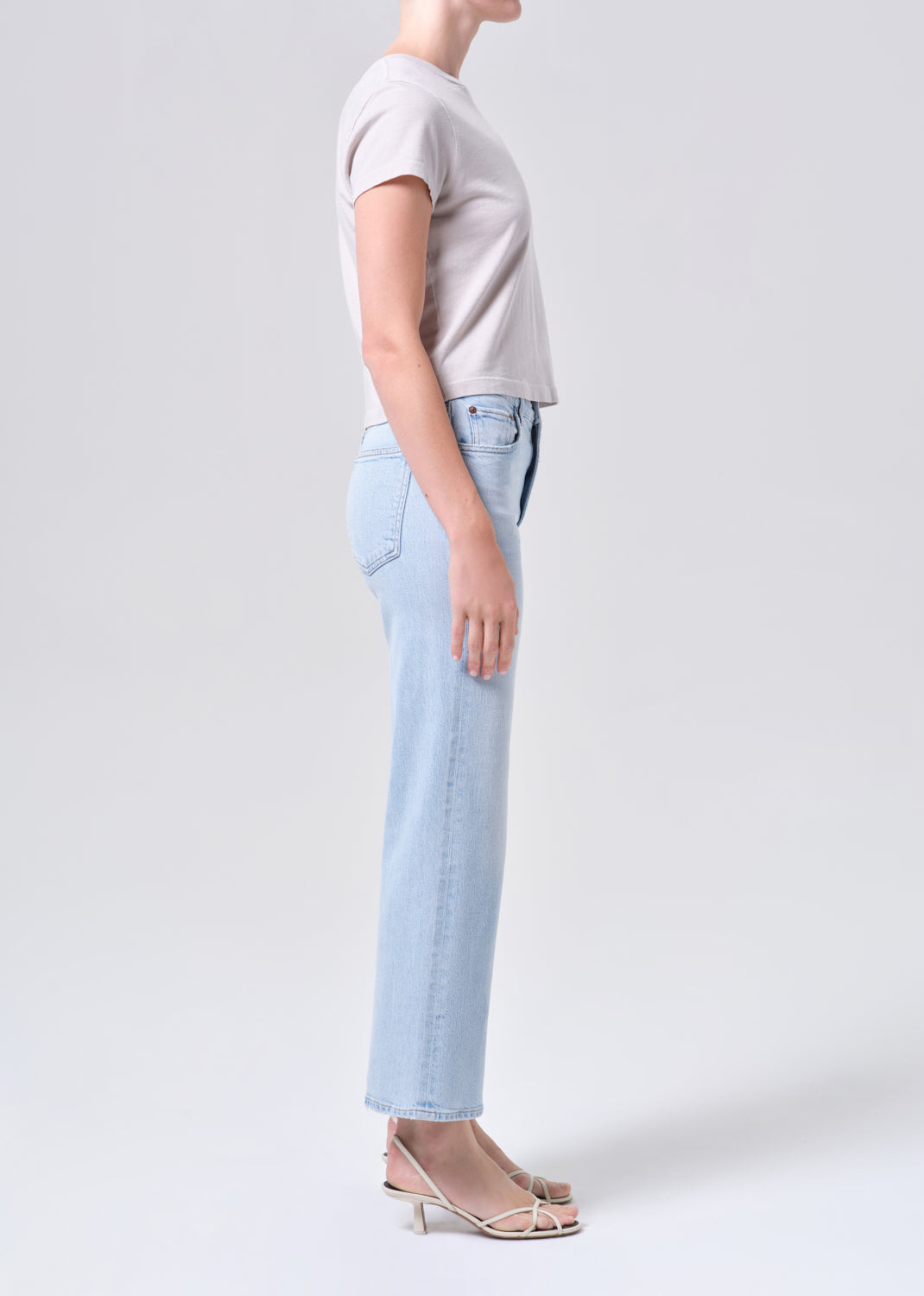 Person wearing a light gray t-shirt and light blue jeans on a white background