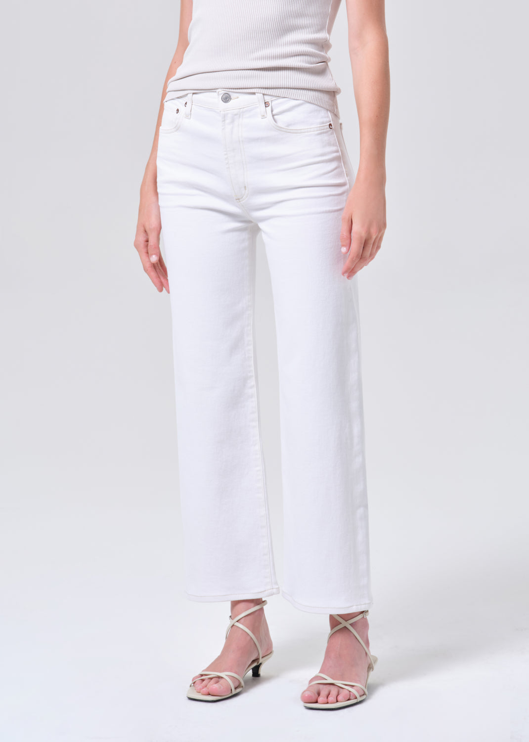 Person wearing white jeans on a plain background