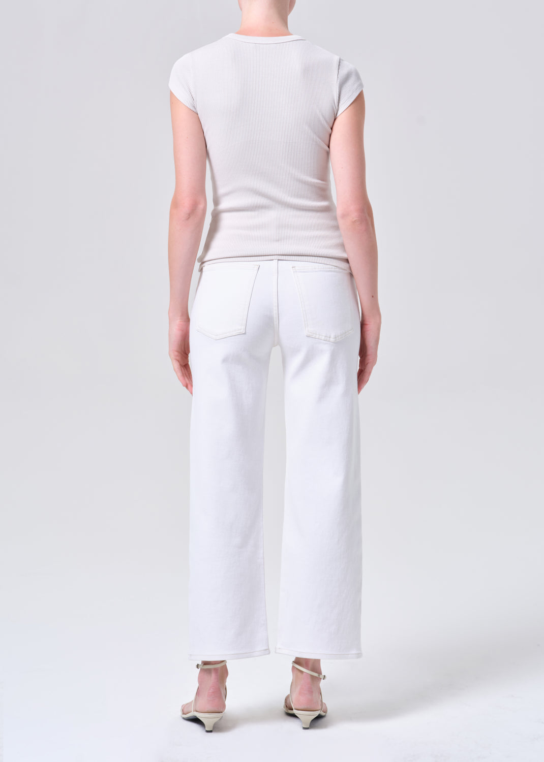 Person wearing a white top and pants on a plain background