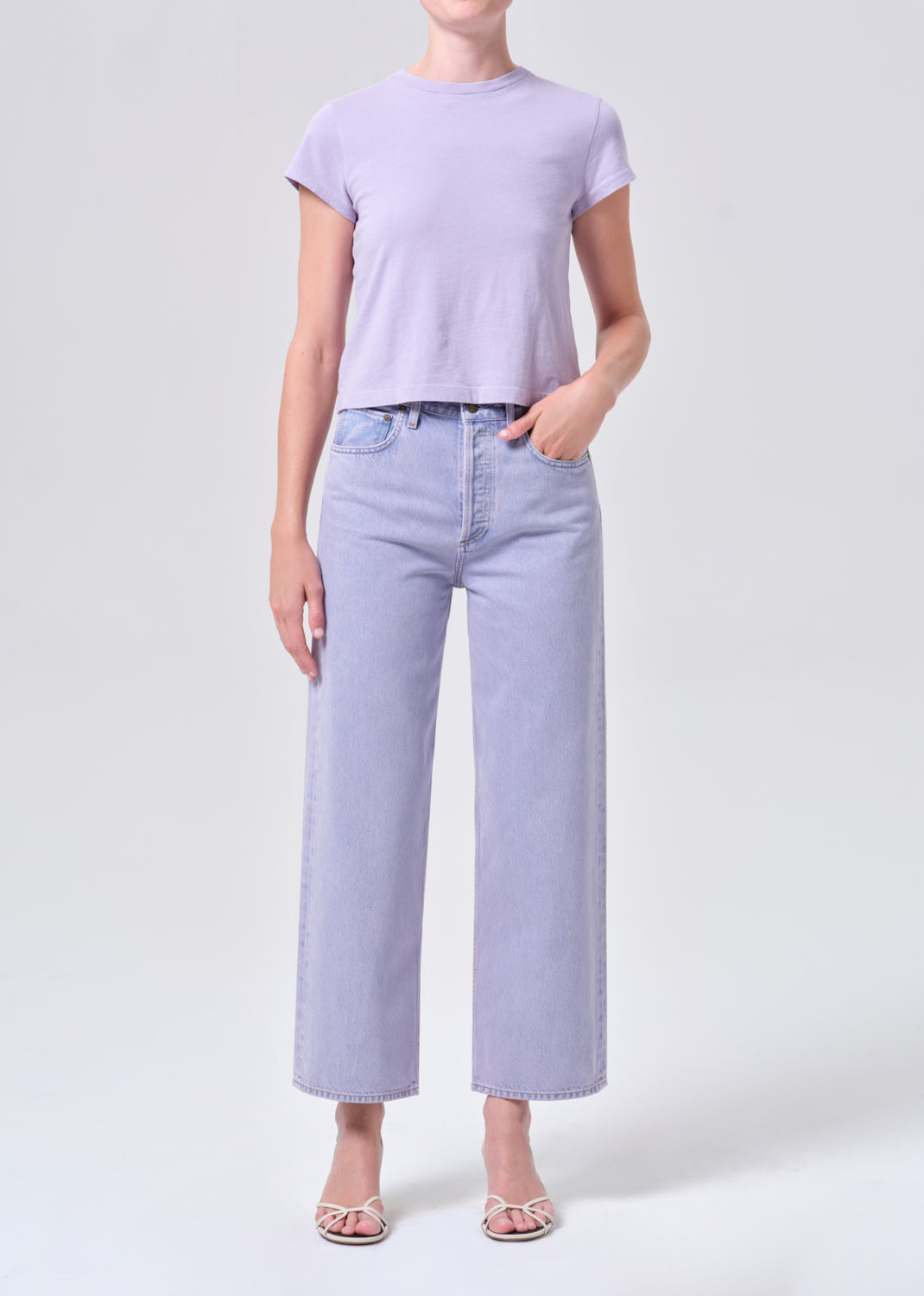 Person wearing a light purple t-shirt and jeans on a white background