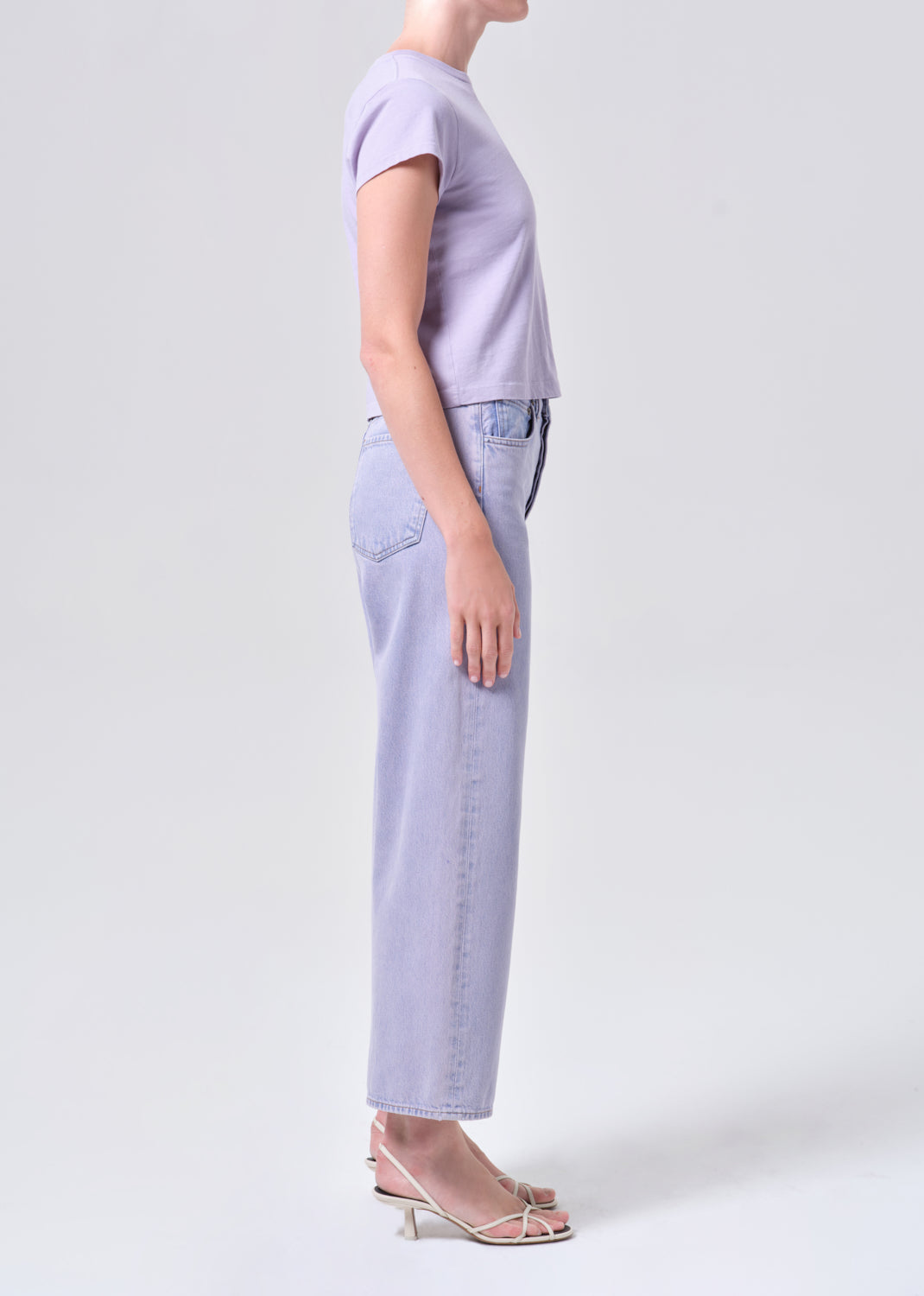Person wearing a light purple t-shirt and jeans on a white background