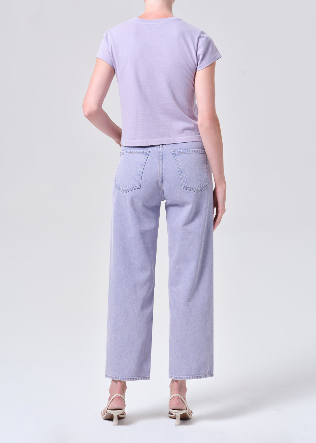 Person wearing a light purple t-shirt and jeans on a white background