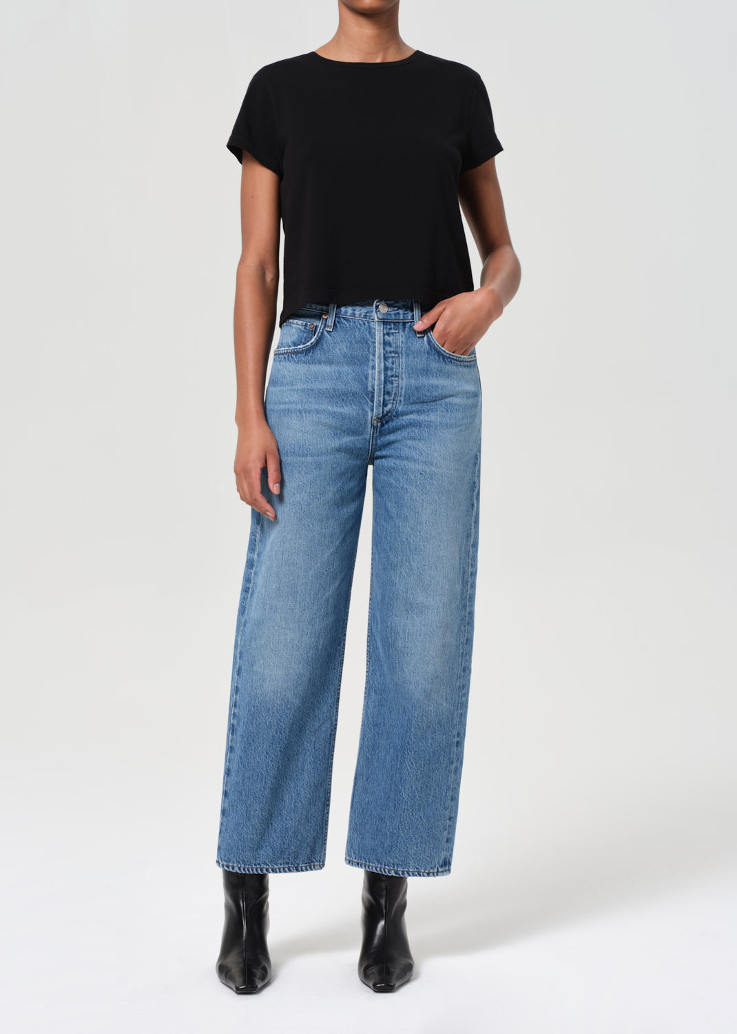 Person wearing a black t-shirt and blue jeans on a white background