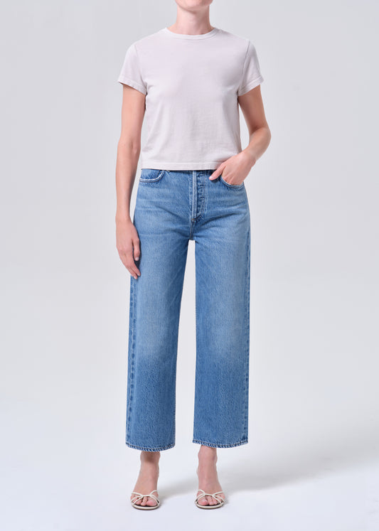 Person wearing a white t-shirt and blue jeans on a light gray background