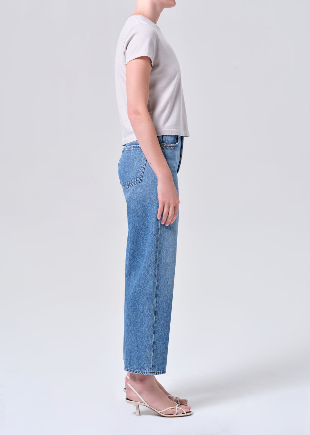 Person wearing light blue jeans and a gray shirt on a white background