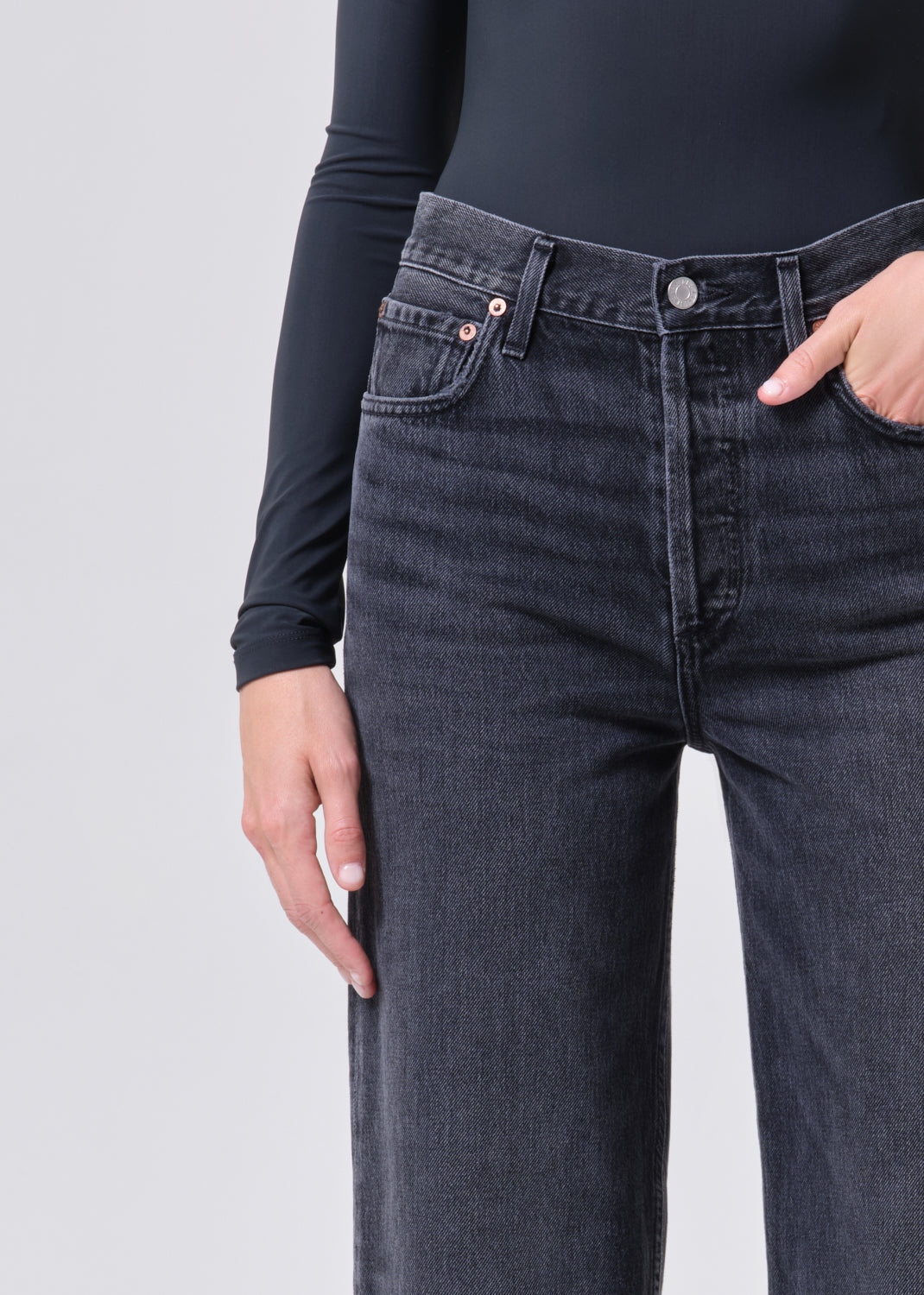 Person wearing dark blue jeans with a plain background