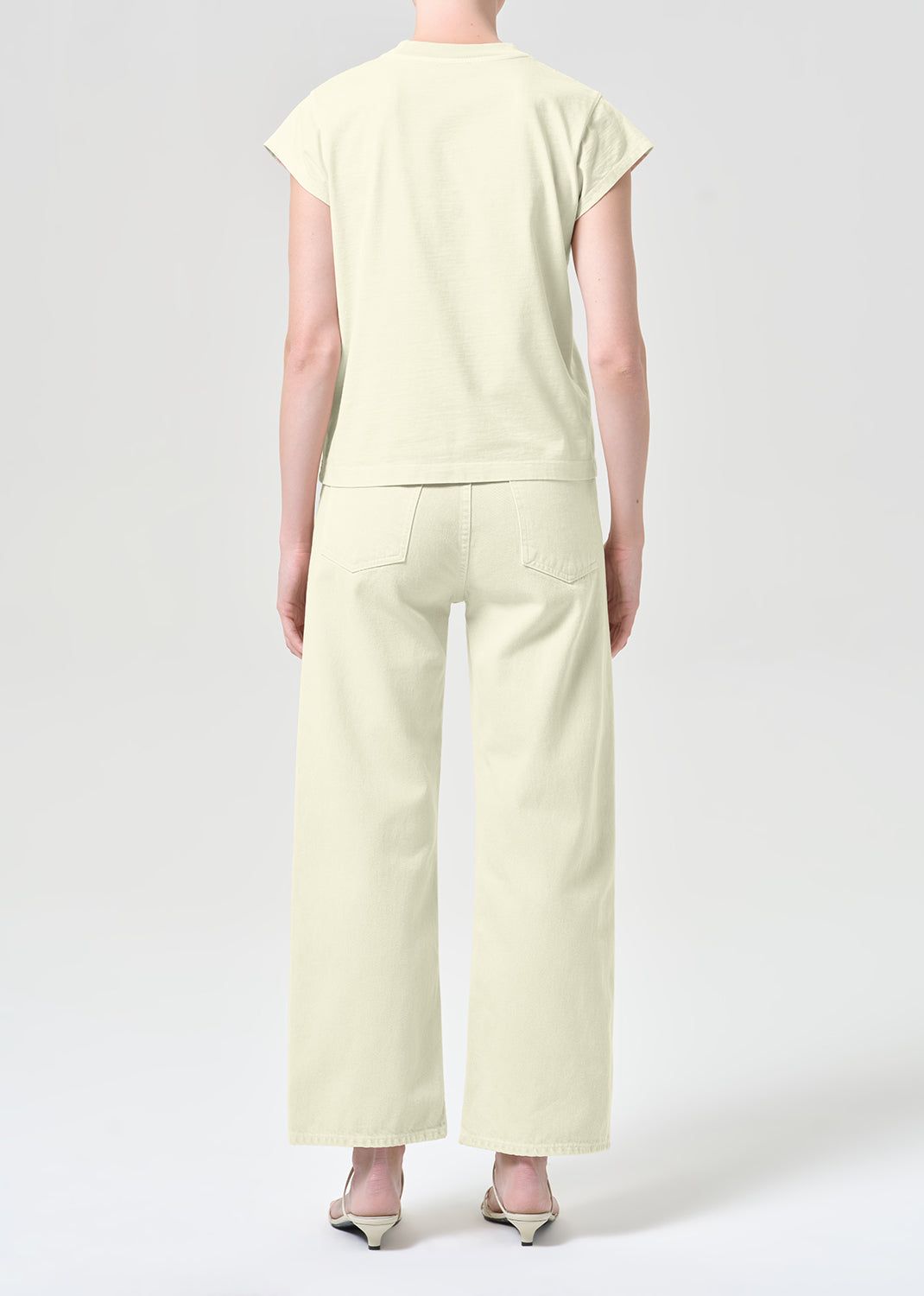 Person wearing a light green outfit with wide-leg pants on a white background